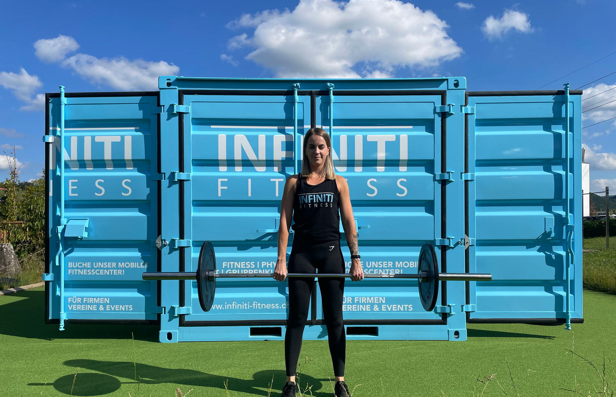 Krafttraining mit Langhantel vor dem blauen INFINITI Outdoor-Container
