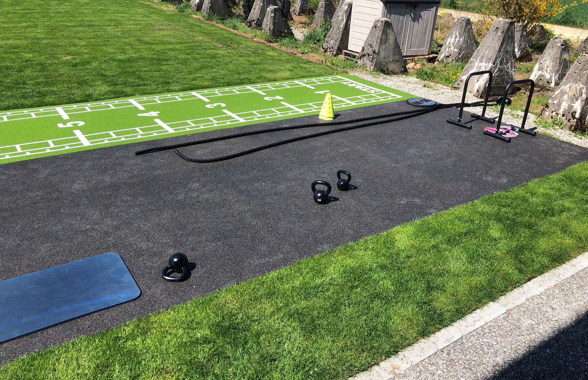 Outdoor-Trainingsfläche mit Kurzhanteln und Markierungsbahn im INFINITI Fitness